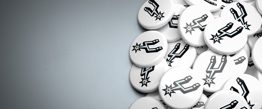 Logos of the American NBA Basketball Team San Antonio Spurs on a heap on a table.
