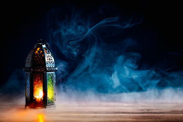 Arabic lantern lights on table with smoke at night. Eid Mubarak, Ramadan Kareem, Islamic holidays greeting card design.