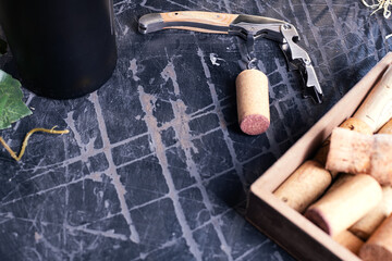 Sommelier knife with wine cork close-up on an old table. Used corks nearby. Space for text.