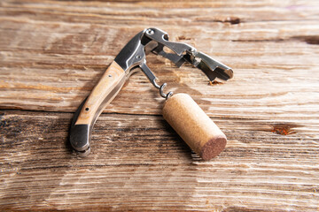 sommelier's knife with a wine stopper on an old wooden table. Space for text.