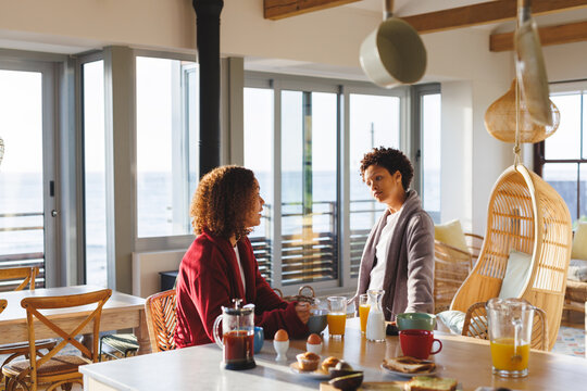 Happy Diverse Lesbian Couple Eating Breakfast In Kitchen