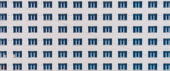 Geometric backdrop with lots of window rows. Simple classic design high-rise building. Realistic concept of office building. Apartment house texture background. Many windows on big wall close-up.