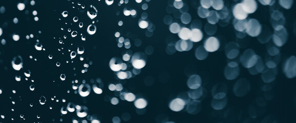 Atmospheric minimal monochrome backdrop with rain droplets on glass. Wet window with rainy drops and dirt spots closeup. Blurry minimalist background of dirty window glass with raindrops close up.