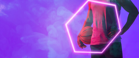 Midsection of biracial basketball player with ball standing by hexagon over smoky background - Powered by Adobe