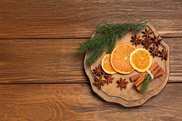 Composition with dry orange slices, anise stars, cinnamon sticks and fir branches on wooden table, flat lay. Space for text
