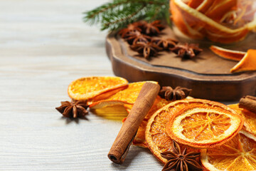 Dry orange slices, anise stars and cinnamon sticks on white wooden table, closeup. Space for text