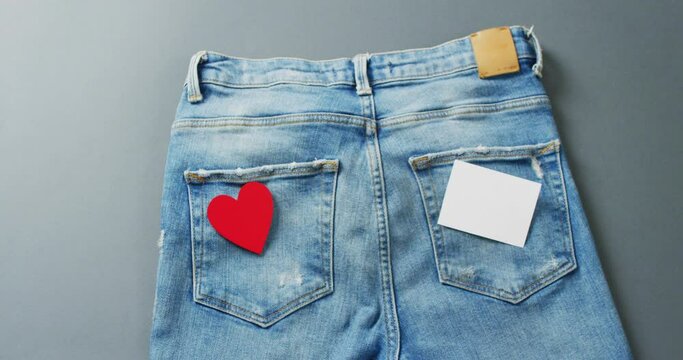 Close up of jeans with heart and white note on grey background with copy space