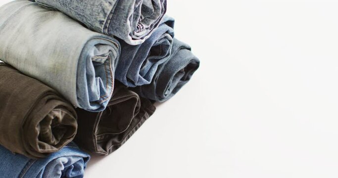 Close up of folded jeans with different shades on white background with copy space
