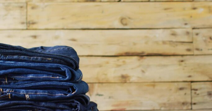 Close up of folded jeans with different shades on wooden background with copy space
