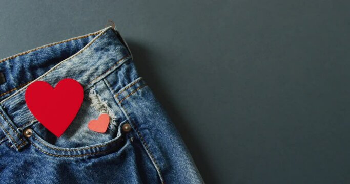 Close up of jeans with red hearts on grey background with copy space