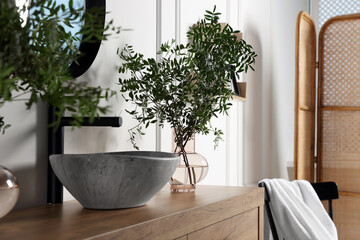 Eucalyptus branches near vessel sink on bathroom vanity. Interior design