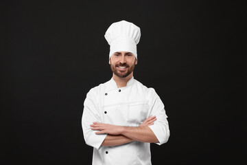 Smiling mature male chef on black background