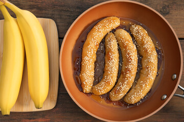 Delicious fresh and fried bananas on wooden table, flat lay