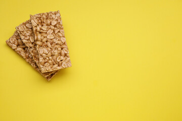 Tasty peanut bars (kozinaki) on yellow background, flat lay. Space for text