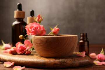 Bowl of essential oil and beautiful roses on wooden table. Aromatherapy treatment