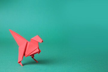 Origami art. Handmade red paper dinosaur on turquoise background, space for text
