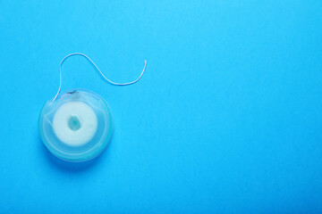 Container with dental floss on light blue background, top view. Space for text