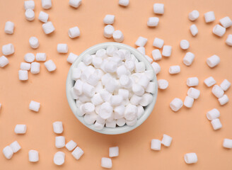 Bowl with sweet marshmallows on orange background, flat lay