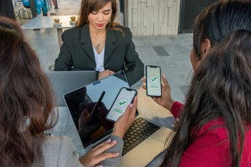 Businesswomen in a meeting pay the bill with their smartphones. On the display: payment completed.