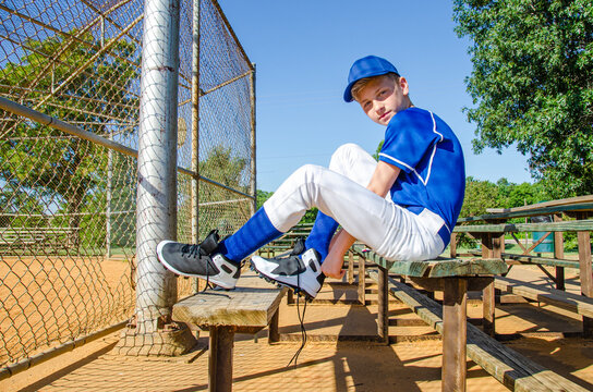 Young Youth Boy Little League Baseball Player Sitting On Bench Putting On Gear