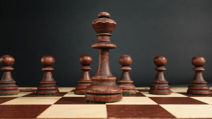 A black chess queen against the background of an army of black pawns.Chess background. Banner for...