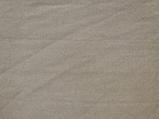 Fototapeta na wymiar Thin light brown textured fabric slightly wrinkled stretched with its thread fibers
