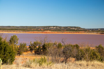 A view of the red colored Abilene Lake and the beautiful Texas Hill Country in the Fall.  People come to hunt and fish at Abeliene State Park.