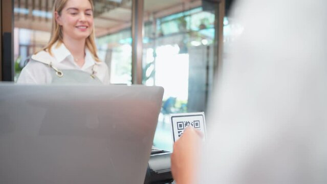 Close up of customer's hand scanning QR code to pay for coffee in cafe.
