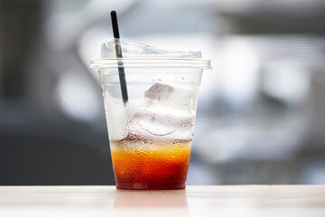 Ice coffee in plastic cup on wooden table in coffee shop.
