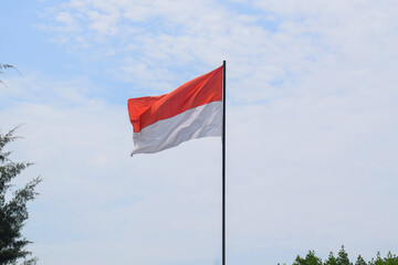 Indonesian Flag, Red and White, waving in the wind with blue sky background