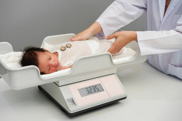 newborn baby weight measurement on digital scales with doctor in hospital
