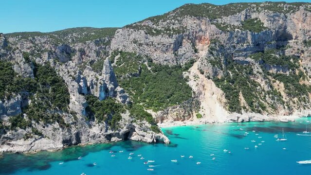 Tourist Boats Enjoy Summer Vacation at Cala Goloritze Beach and Rock Formation in Sardinia, Italy - Aerial 4k Circling