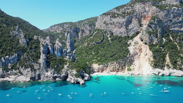 Tourist Boats Enjoy Summer Vacation at Cala Goloritze Beach Rock Formations in Sardinia, Italy - Aerial 4k
