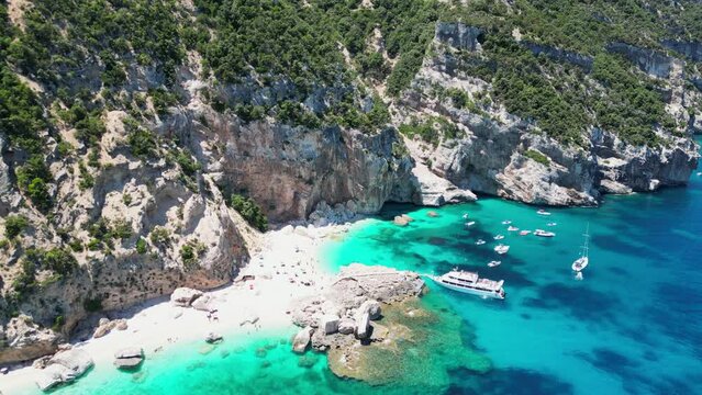 Boat Tour Excursion pick up Tourist People at Cala Mariolu Beach, Baunei Coast, Sardinia, Italy - Aerial 4k Circling