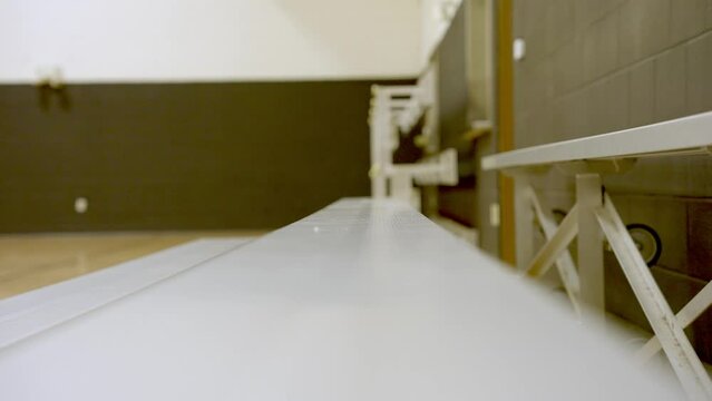 Tracking in along empty wooden bleachers on Basketball gymnasium, Selective focus