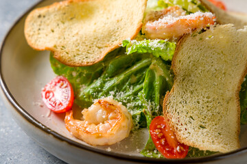 salad caesar with shrimps on white plate macro close up