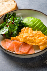 Scramble with salmon and avocado on plate macro close up vertical