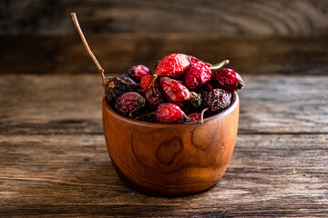 Dry rose hips in a wooden cup on the kitchen table.