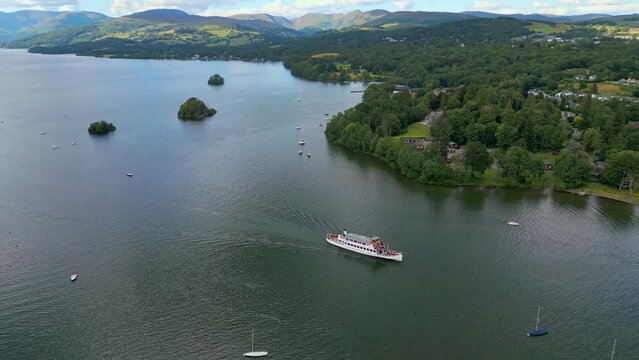 Cinematic aerial drone view of Bowness-on-Windermere. Showing the small lakeland town and the Lake. Boats, cruse, small ships. Lake District National Park, Cumbria, UK