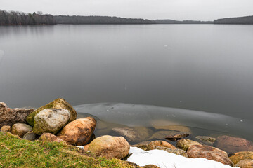 Icy cold reservoir on winter day with stones.