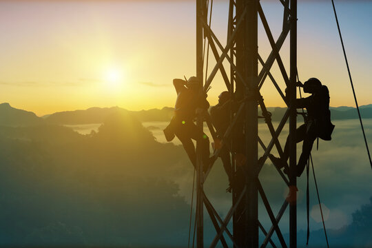 Silhouette workers on construction crews to work on high ground heavy industry and connection development, distribution electrical concept. Extension of high-voltage towers on nature background.