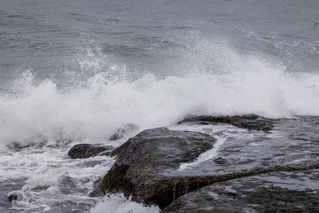 Beautiful Nature scene of sea wave hitting on the black stone shoreline