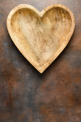 Rustic wooden heart shaped bowl on a rustic background
