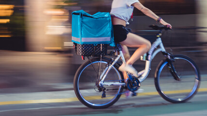 Unrecognizable young woman doing delivery on a bicycle with motion blur.
