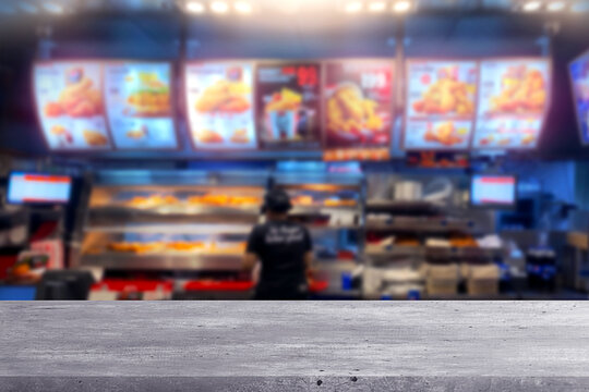 Modern wooden table with blurred fast food restaurant background. Has junk meal menu set and many  fried chicken, hamburger, french fries.