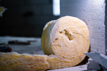 A roll of glass wool insulation close-up at a construction site with a blurred background....