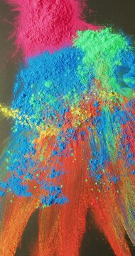 Vertical video of close up of colourful powders on black background, with copy space