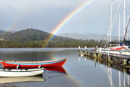 Pier with rainbow and yachts near the Wooden Boat Centre at Franklin, Cygnet, Tasmania.