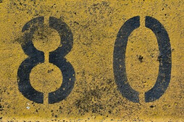The number eighty, 80,  in black and yellow.