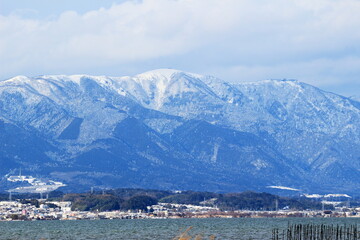 Fototapeta na wymiar 琵琶湖越しに見る雪の積もった湖西の山